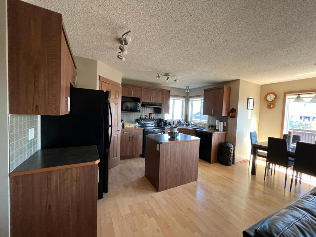 a large kitchen with wooden cabinets and a kitchen island at Spacious comfortable Air-Conditioned. Near airport! in Calgary