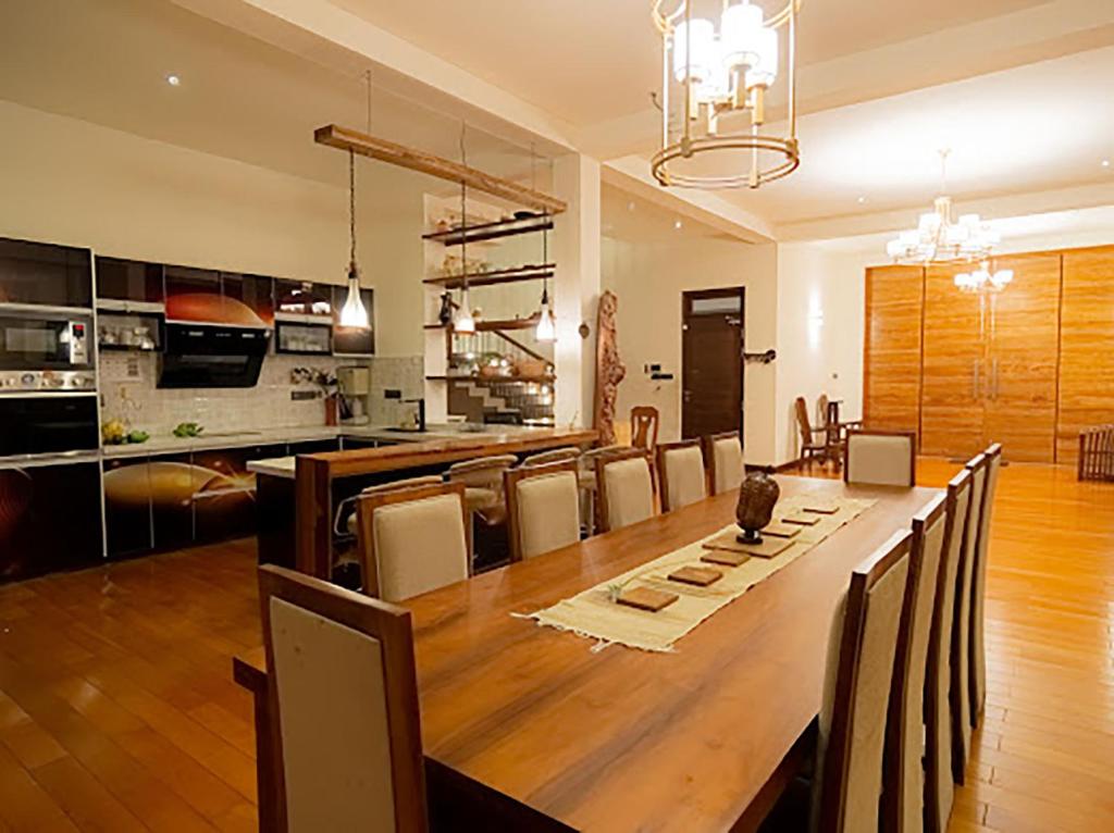 a dining room and kitchen with a large wooden table at Royal Retreat Kandy in Kandy