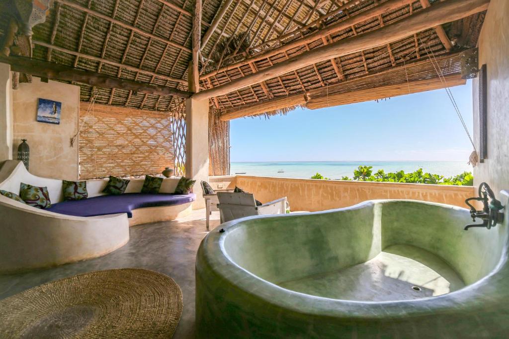 a bath tub in a room with a view of the ocean at Mr Kahawa Lofts in Paje