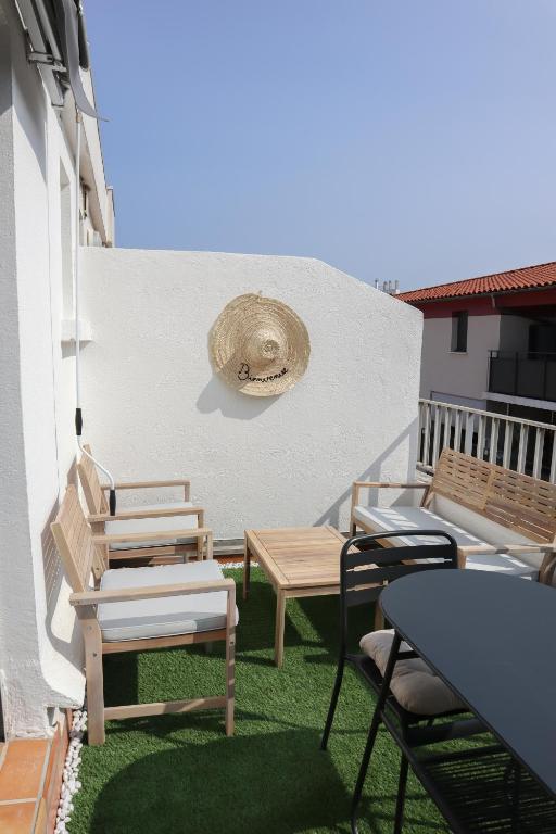 d'une terrasse avec des chaises, des tables et un chapeau mural. dans l'établissement Studio rénové centre ville, clim et terrasse, à Montpellier