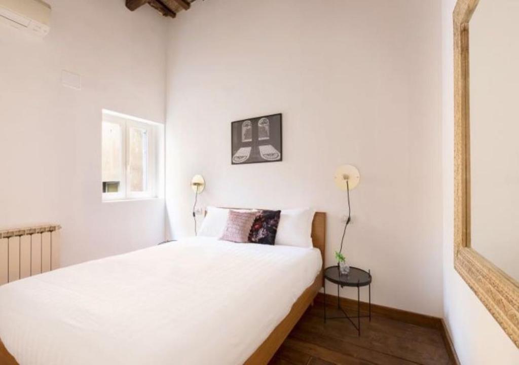 - une chambre blanche avec un lit et un miroir dans l'établissement Barberini Luxury Apartment, à Rome