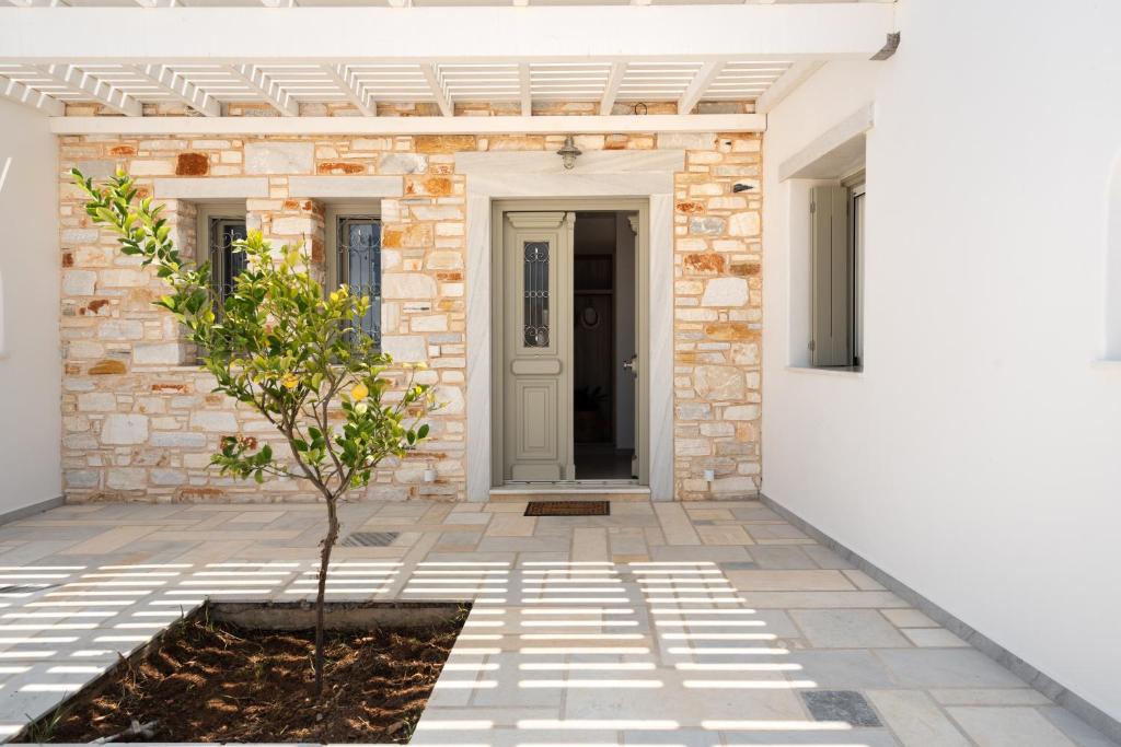 a front door of a house with a tree in a courtyard at Santa Maria Mare in Naousa