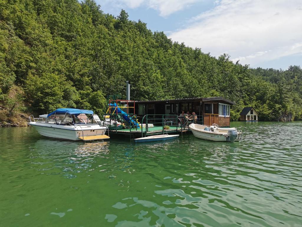 três barcos estão ancorados num lago com uma casa em Splav Drina-Višegrad em Višegrad