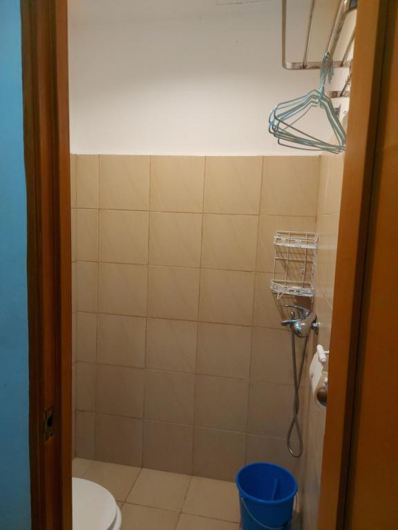 a bathroom with a toilet and a blue bucket at Fully Furnished Staycation - Neflix, Pool,Can cook near Mactan Airport in Maribago