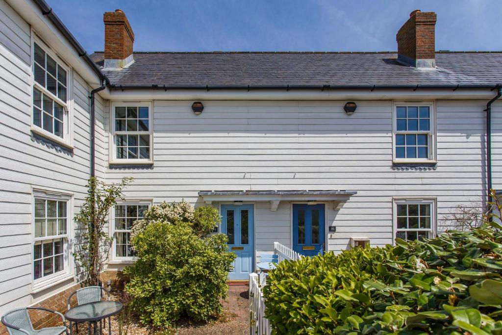 una casa blanca con una puerta azul en Sands End, en Camber