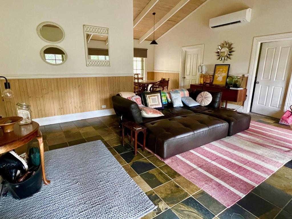 a living room with a leather couch and a rug at Kookaburra Cabin in Warburton