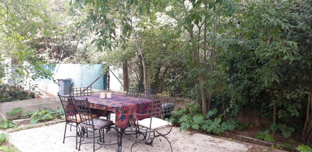uma mesa e cadeiras num jardim com árvores em chambre d'hôte chez l'habitant em Sète