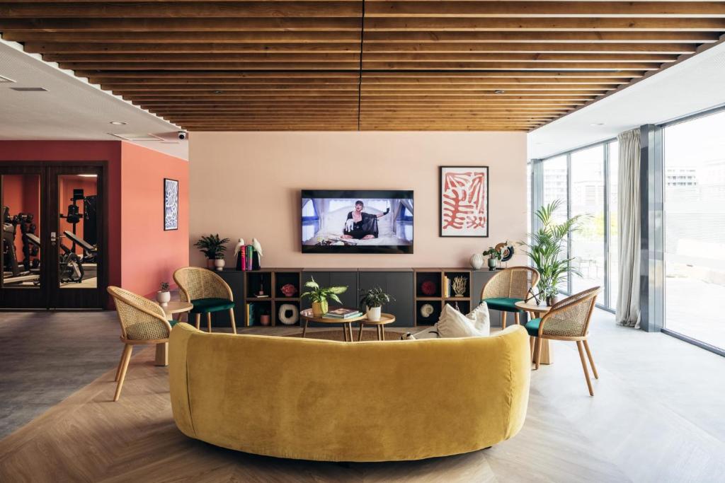 sala de estar con sofá amarillo y sillas en Soto House Pamplona, en Pamplona