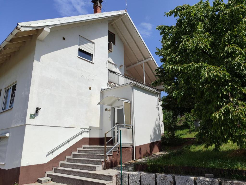 un edificio blanco con escaleras junto a un árbol en Esma, en Vogošća