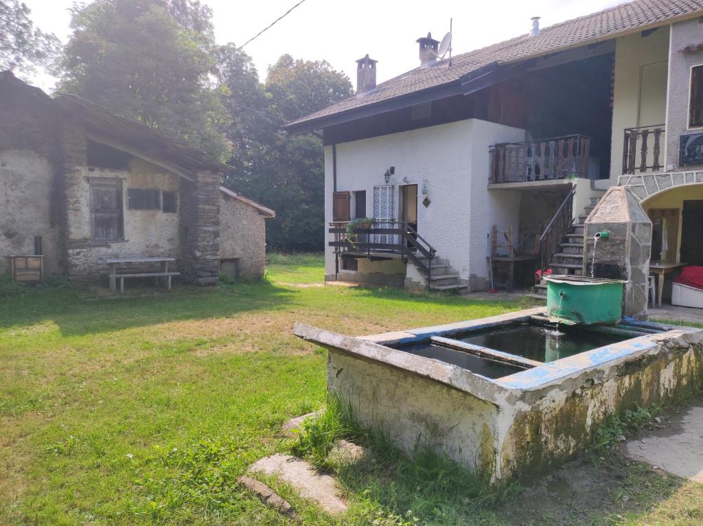 ein altes Haus mit einem Teich im Hof in der Unterkunft Vivere in un bosco Casa Leonardo in Villar Perosa