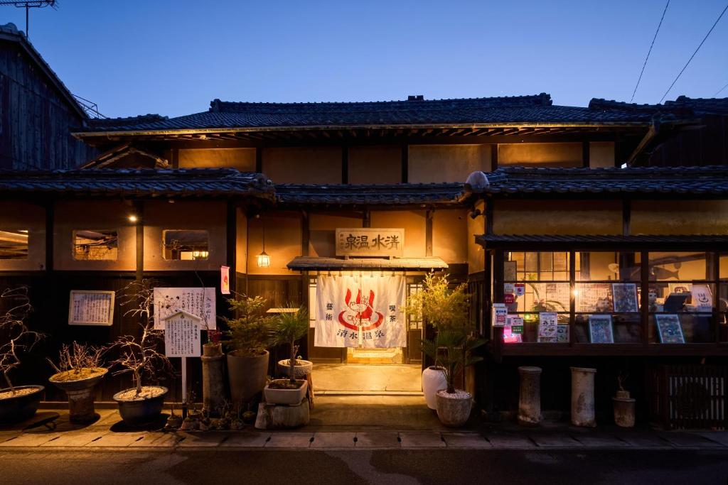 una tienda frente a un edificio con plantas delante en 一棟貸切宿 空と家 本棟, en Tadotsu