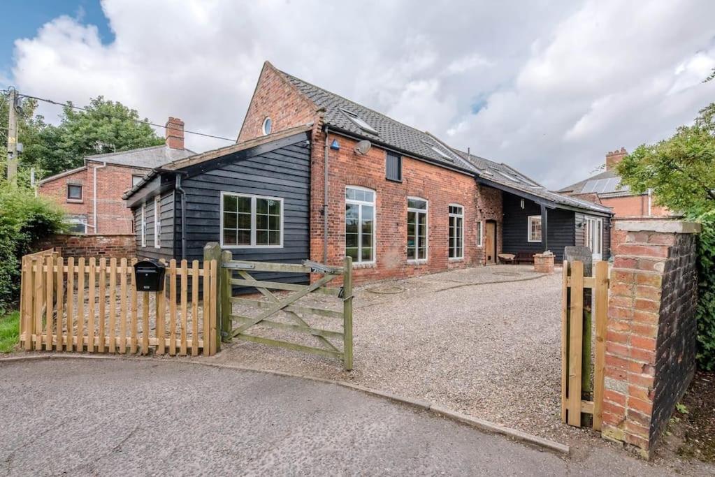 a house with a wooden gate and a brick building at The Old Coach House, Leiston in Leiston