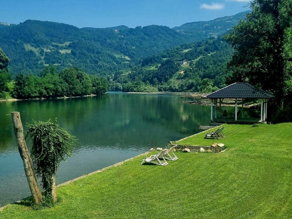 un lac avec un kiosque et des chaises sur l'herbe dans l'établissement Brvnara DRINA Wooden House Drina, à Drlače