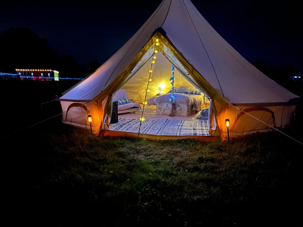 a tent with a bed in a field at night at Country View Camping in Bratton