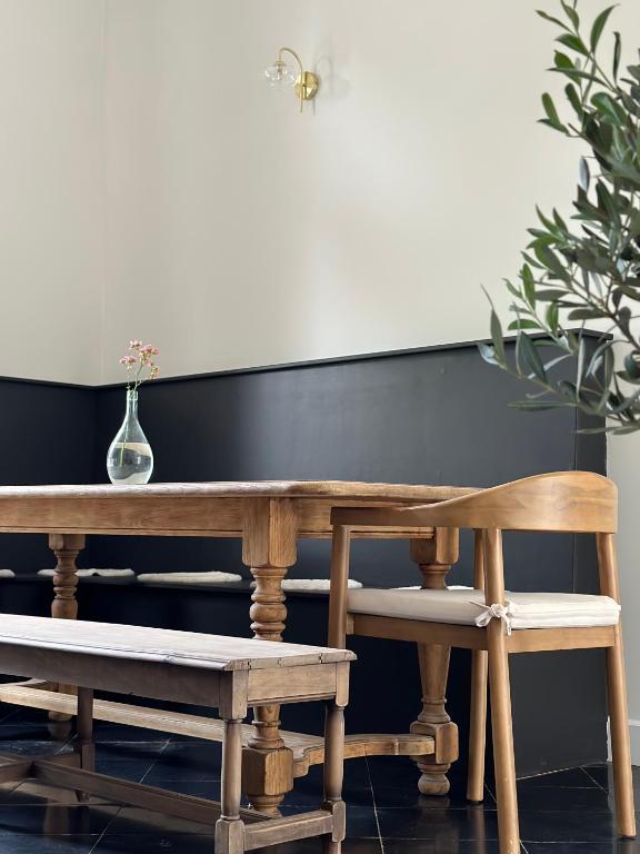a wooden table and bench with a vase and a plant at Maison Comtale in Rochefort