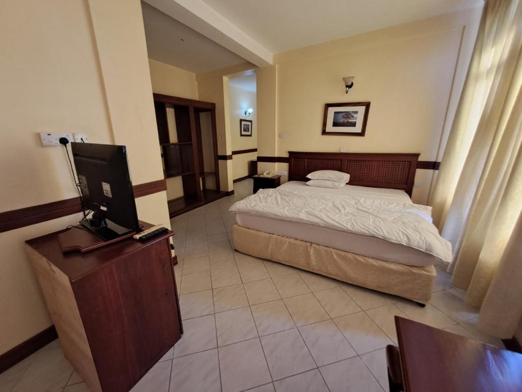 Moshi Leopard Hotel في موشي: غرفة نوم بسرير وتلفزيون بشاشة مسطحة