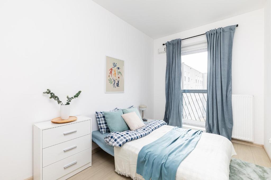 a white bedroom with a bed and a window at SuperApart Mińska apt91 in Warsaw