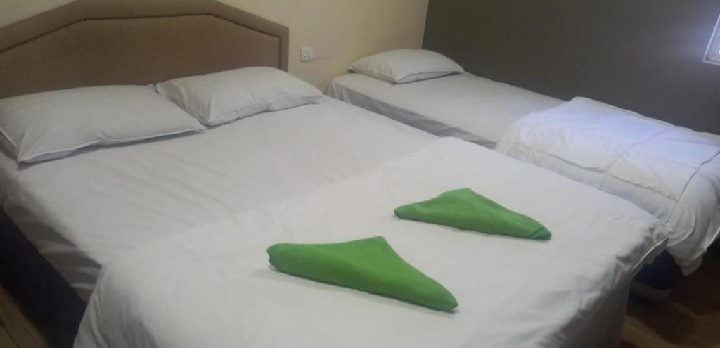 2 camas con almohadas verdes en Q one hotel, en Kampung Dengkil