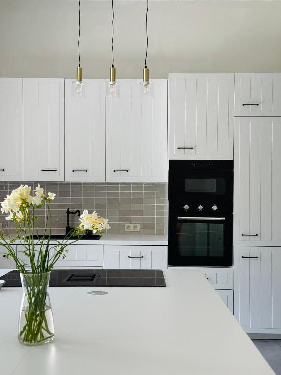 a white kitchen with a vase of flowers on a counter at Maison Comtale in Rochefort