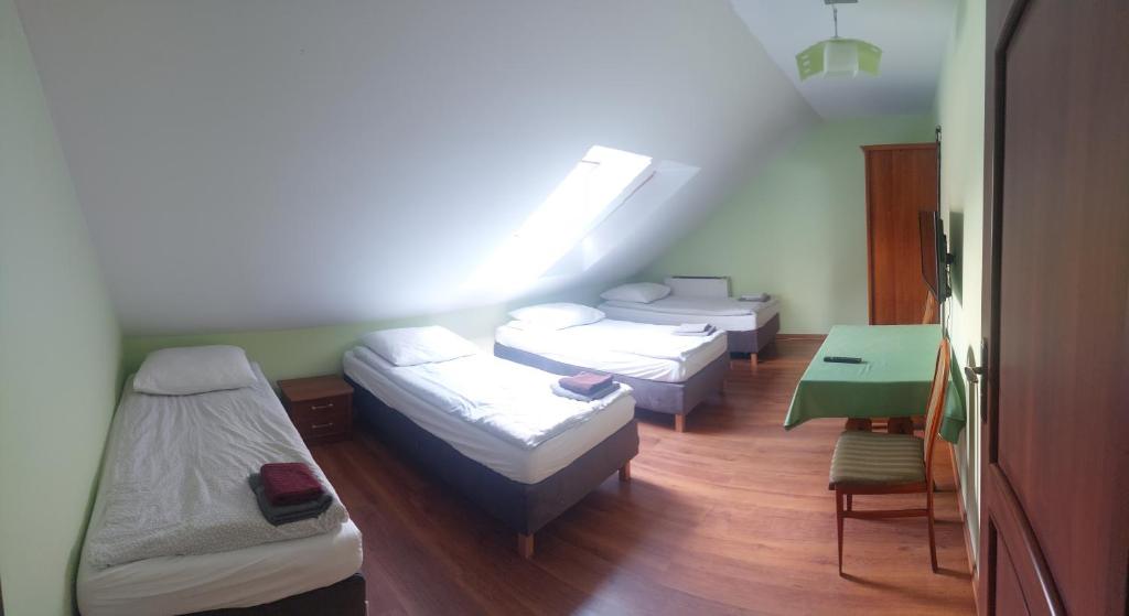 a room with three beds and a table and a window at Zajazd Pod Dyliżansem in Kościelec