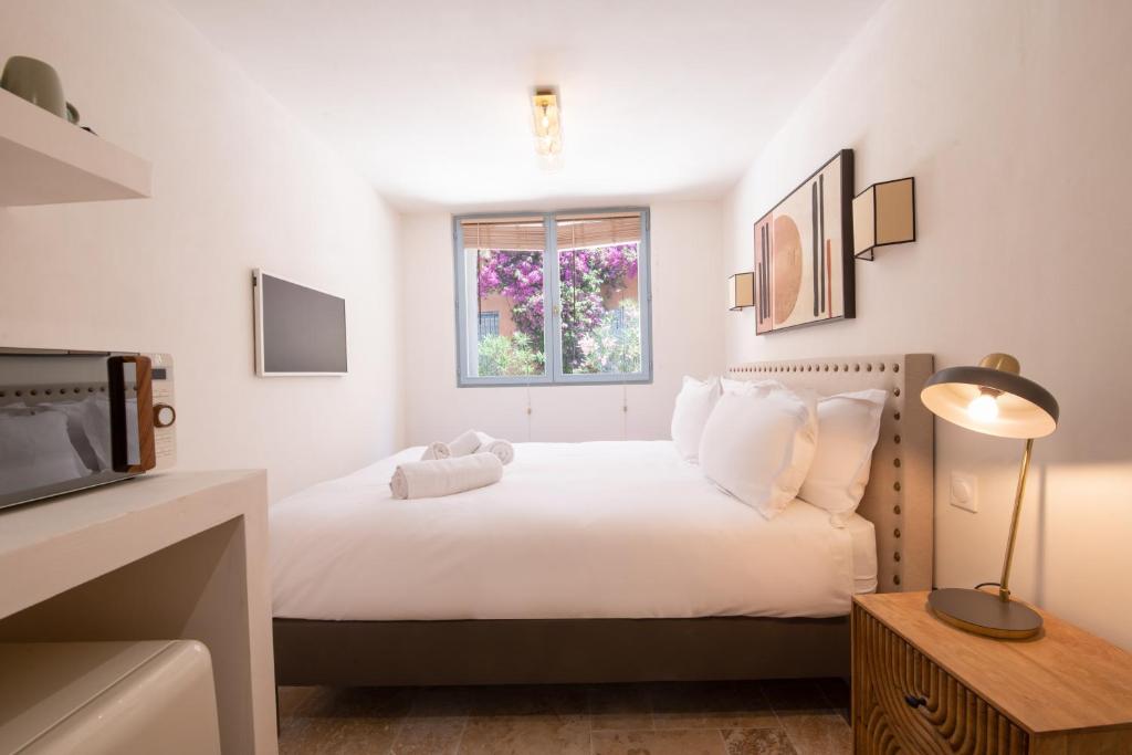 ein Schlafzimmer mit einem weißen Bett und einem Fenster in der Unterkunft Pick A Flat's Apartments in Saint-Tropez - Rue des Bouchonniers in Saint-Tropez