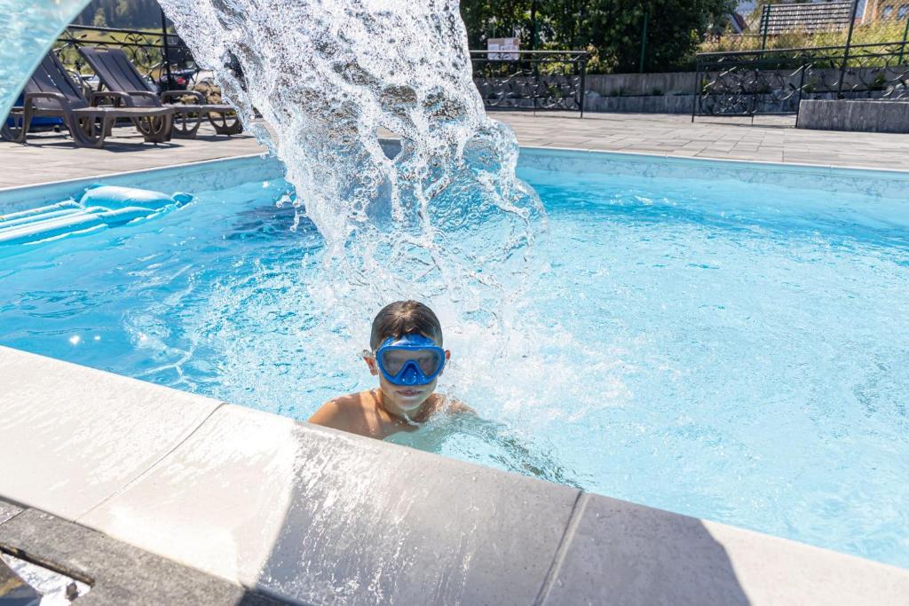 a boy in a swimming pool with a water fountain at „Malućko Chata” in Zakopane