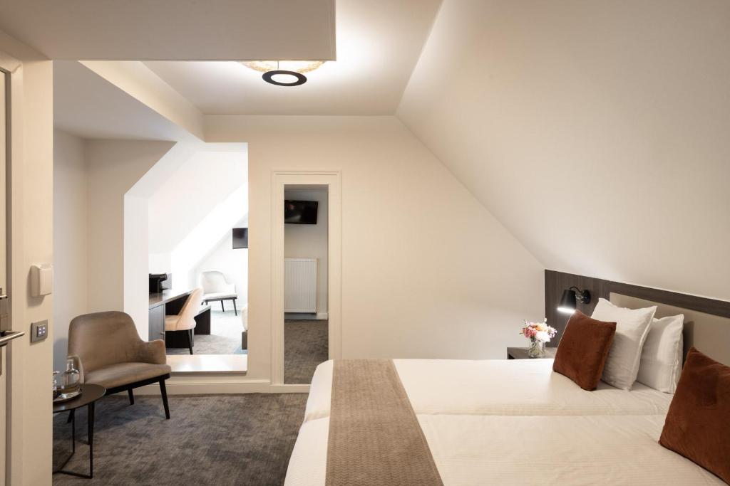 a bedroom with a king sized bed and a chair at Dukes' Academie Brugge - by Dukes' Hotel Collection in Bruges