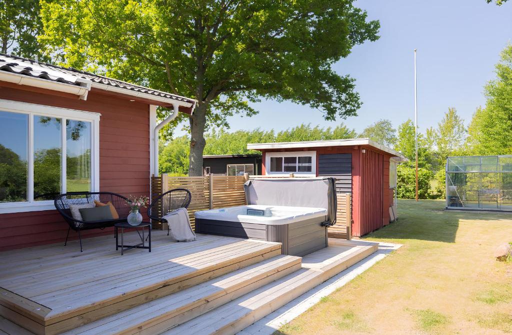 un bain à remous sur une terrasse à côté d'une maison dans l'établissement Renovated cottage with SPA located 200 m from the sea, à Ljungbyholm
