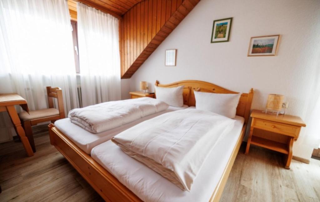 Schlafzimmer mit einem Bett mit weißer Bettwäsche und einem Fenster in der Unterkunft Drexl Gasthof Shiro in Schondorf am Ammersee