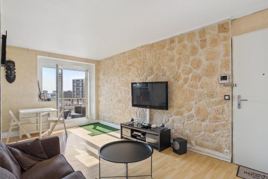 a living room with a tv on a stone wall at Le Calme à deux pas de Paris in Nanterre