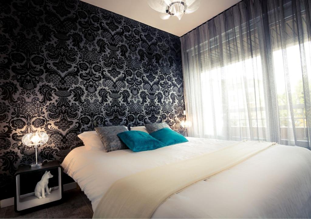 une chambre avec un grand lit blanc avec des oreillers bleus dans l'établissement Golden Beach parking proche du lac, à Annecy