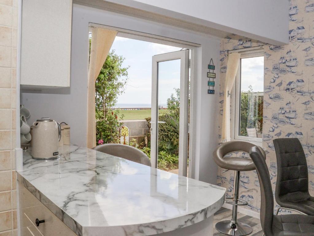 eine Küche mit einer Marmorarbeitsplatte und einem Fenster in der Unterkunft Wavecrest in Hornsea