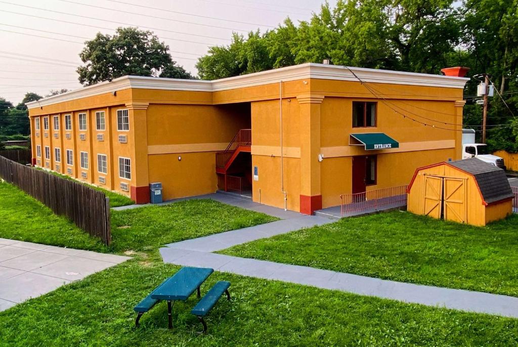 a yellow building with two benches in front of it at Super 8 by Wyndham Gloucester in Gloucester City