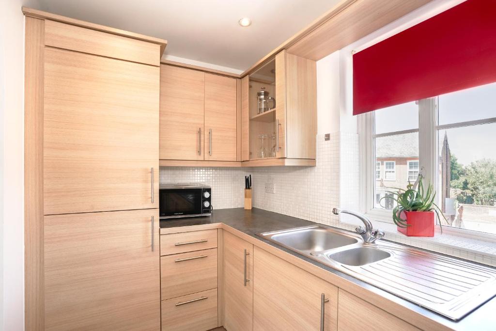 a kitchen with wooden cabinets and a sink and a window at Garland Rd Colchester in Colchester