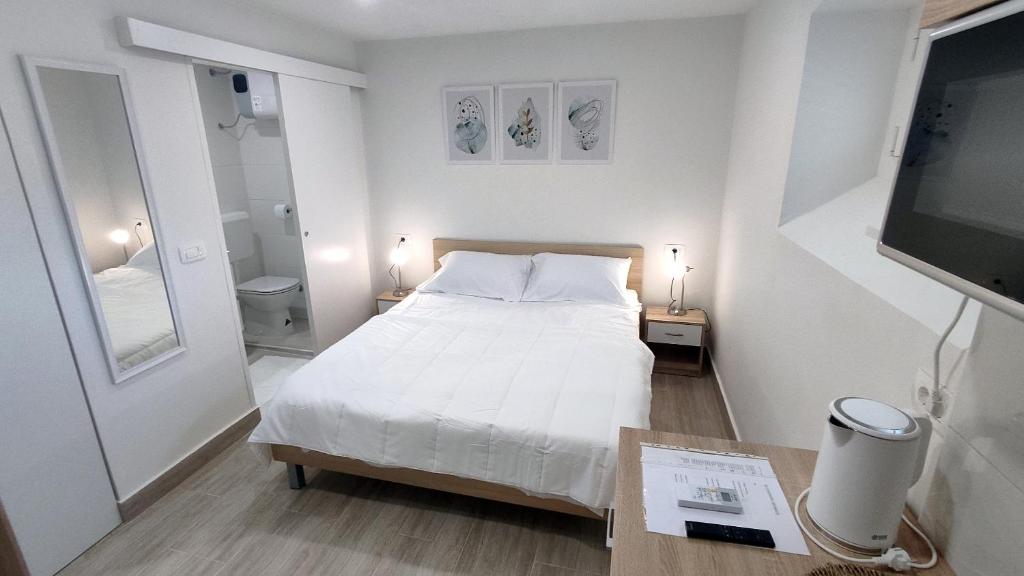 a small white bedroom with a bed and a television at 2023 Bruno - wifi and parking available in Portorož
