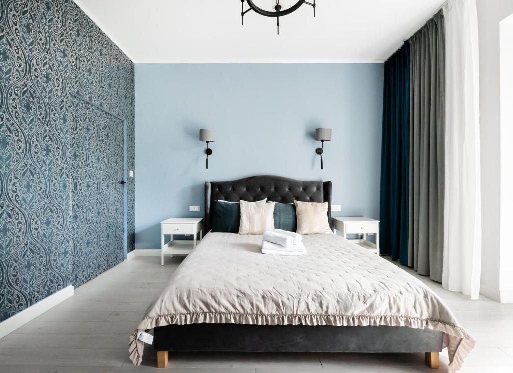 a bedroom with a large bed with blue walls at Wiejska Glamour Apartment in Warsaw