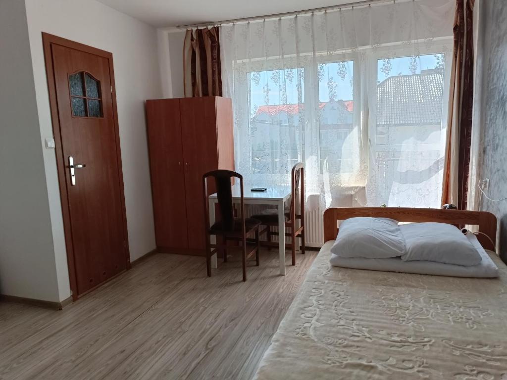 a bedroom with a bed and a table and a window at Pokoje Gościnne Heland in Jastrzębia Góra