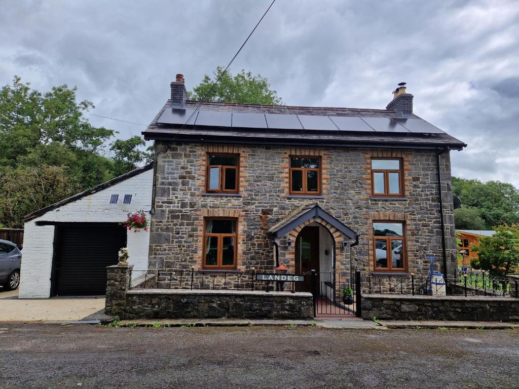 a stone house with a solar roof on a street at Cosy Riverside home in Llanwrda
