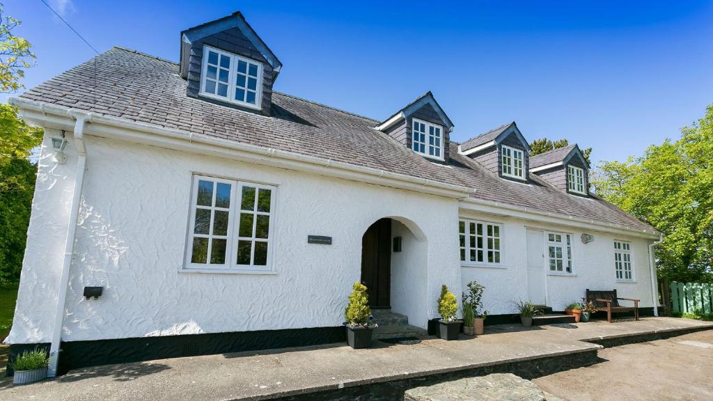 a white house with a black roof at Glan Gors Felin in Llanrhyddlad