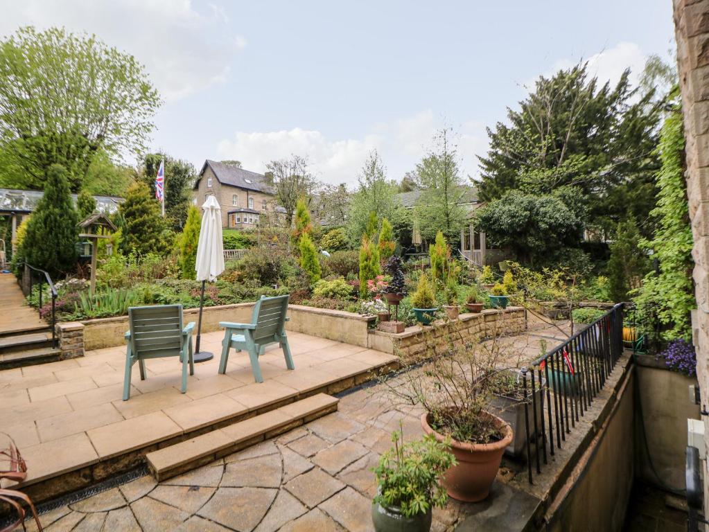a patio with two chairs and an umbrella in a garden at Garden Apartment in Buxton