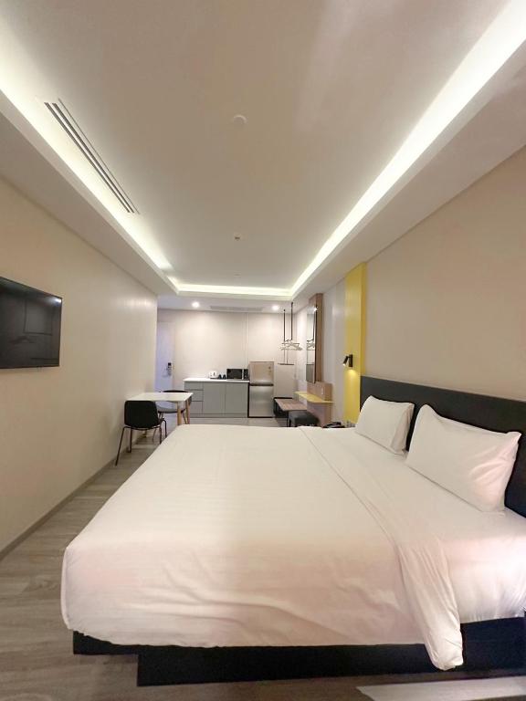 A studio room with a large double bed, television, dining table and kitchenette.
