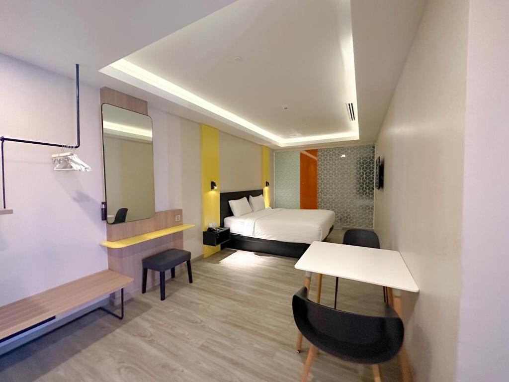 A studio-style room combining a double bed, dining table and dressing counter.