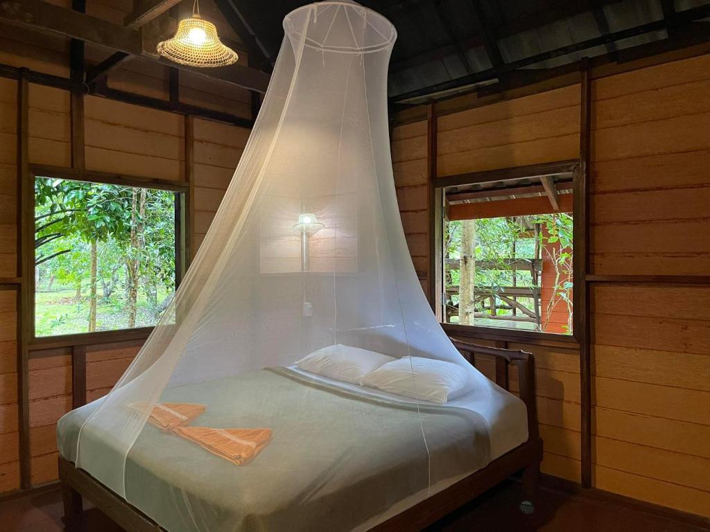 Bett mit Moskitonetz darüber in einem Zimmer in der Unterkunft Khao Sok Green Mountain View in Khao Sok