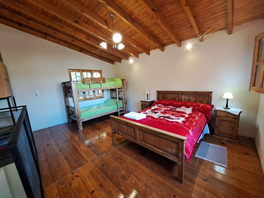 a bedroom with a large bed and a wooden floor at AMANECER DORADO - Cabaña en Tunuyán in Tunuyán
