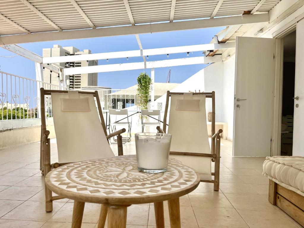 a table and chairs on a balcony with a drink on it at Neve Tsedek Rooftop in Tel Aviv