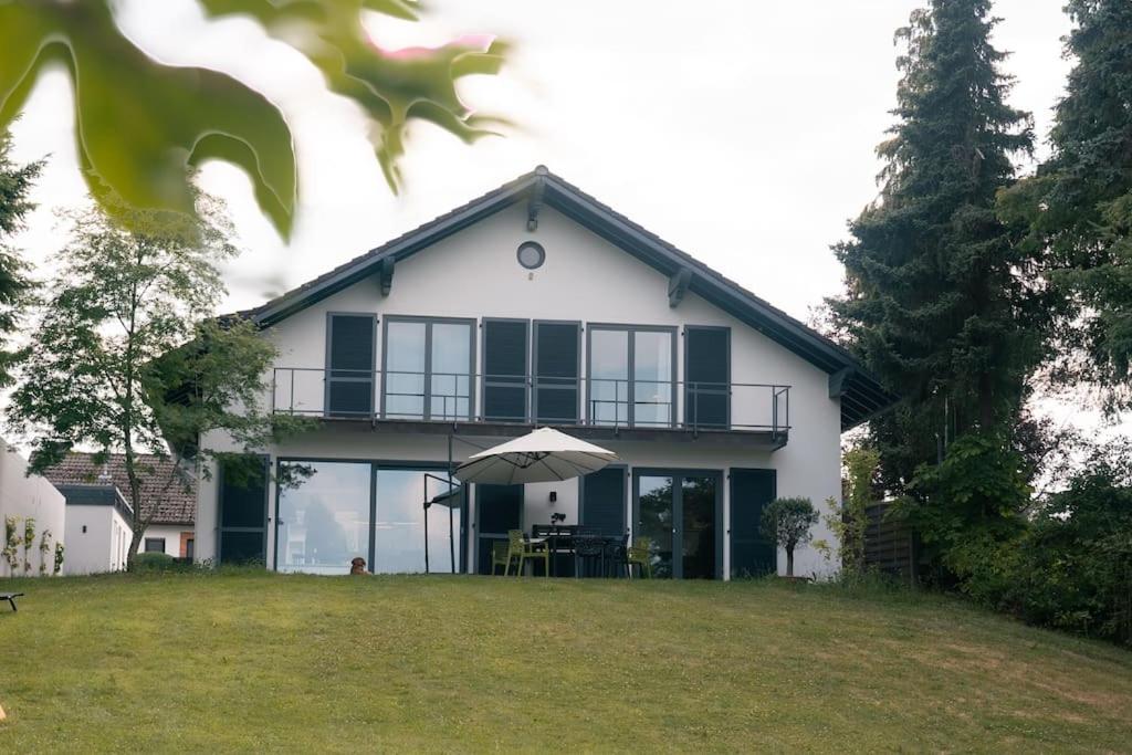 Cette maison blanche dispose d'un balcon et d'un parasol. dans l'établissement Eifel21 - stilvolles Haus in der Vulkaneifel, à Bleckhausen