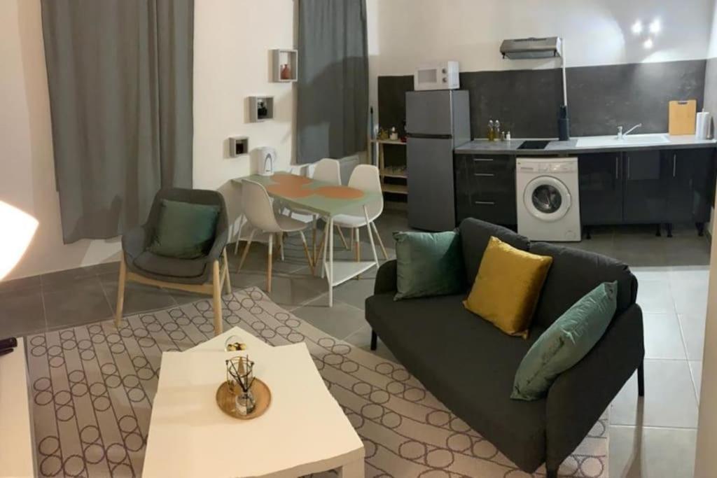 ein Wohnzimmer mit einem Sofa und einem Tisch in der Unterkunft Studio cosy, rénové en plein centre-ville in Manosque