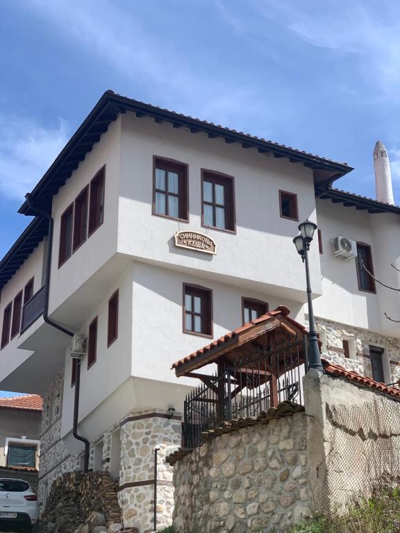 a large white house with a stone wall at Сининкова Къща in Melnik