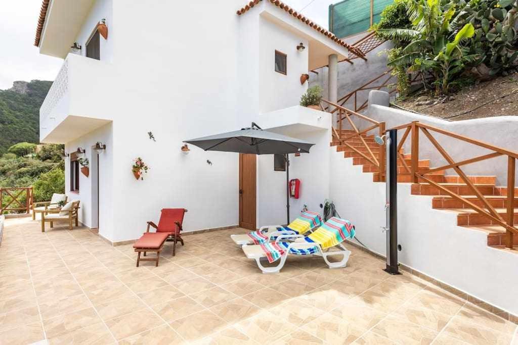 a patio with chairs and an umbrella and stairs at Casa en Anaga Senderismo naturaleza y desconexión in Santa Cruz de Tenerife
