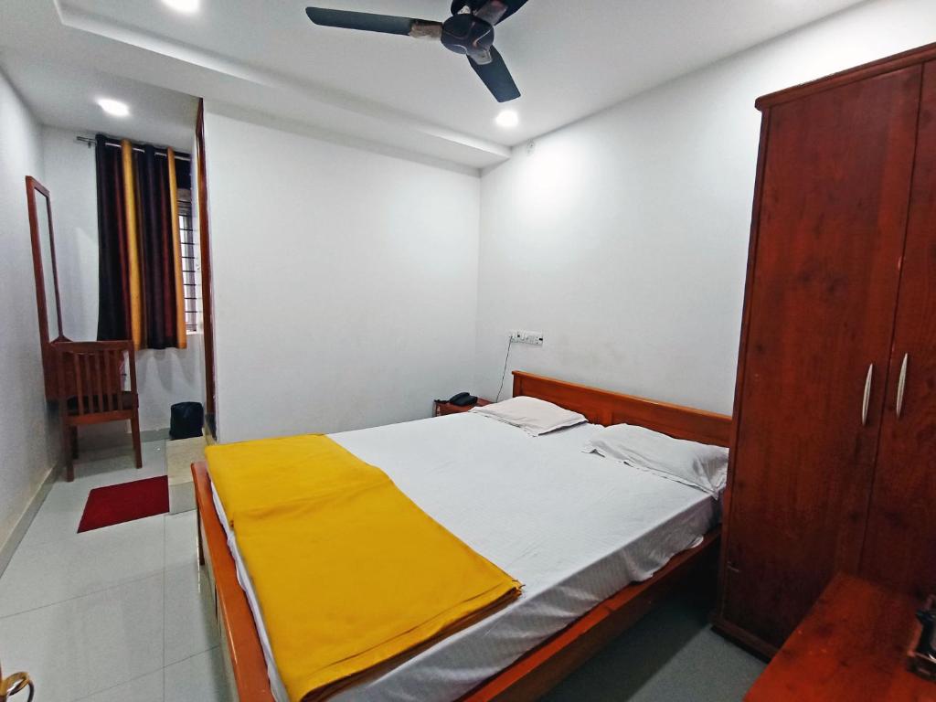 a bedroom with a bed with a yellow blanket on it at STAYMAKER Shri Shakti Residency in Hubli